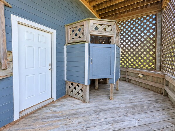 A wooden deck with a door and a blue cabinet.