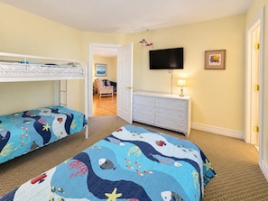 A child's bedroom with bunk beds, a dresser, a television, and a door leading to another room. - Goldenberg - 🏄Enjoy Spectacular Views from this 4 BR Oceanfront Home🏄 (Southern Shores)