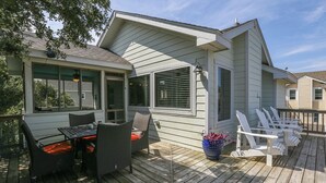 A covered outdoor area with a table and chairs, a potted plant, and a deck railing. - Luap's Place - Oceanside 5 BR home w/ Private Pool and Hot Tub (Corolla)