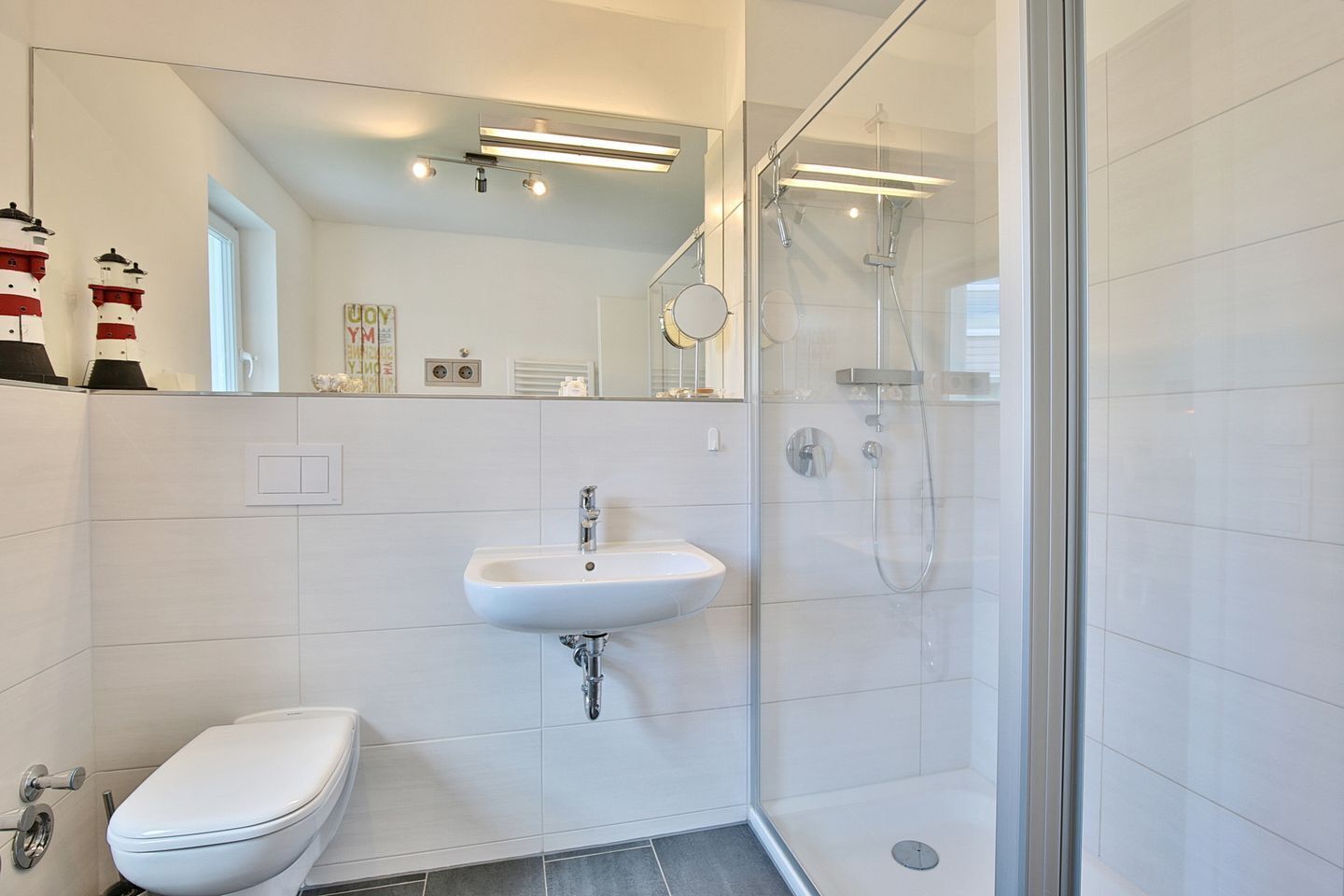 Une salle de bain moderne avec une douche à parois de verre, un lavabo blanc et des toilettes.