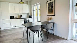 Una cucina moderna con mobili bianchi, un piano di lavoro nero e un tavolo da pranzo con quattro sedie.