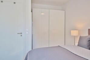 Ein Schlafzimmer mit Bett, Kleiderschrank, Lampe und einer Wandregal.