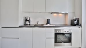 A modern kitchen with white cabinets, a stainless steel oven, and a coffee maker.