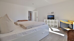 A bedroom with a bed, a desk, and a television.