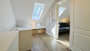 Une chambre à coucher aménagée dans un espace ouvert, avec une lucarne, un lit, une table de chevet, un canapé et un petit coin salon.