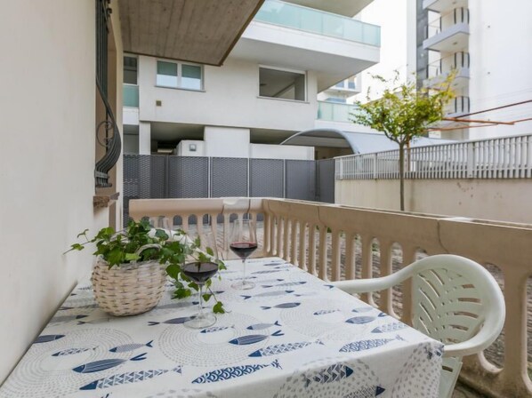 A balcony with a table set for two, a wicker basket, and a potted plant.
