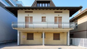 Un bâtiment à deux étages doté d’un balcon, d’une façade en briques et surplombant un ciel dégagé.