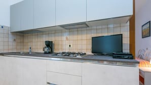 Une cuisine moderne dotée d’un îlot central, d’une cuisinière à gaz, d’une machine à café et d’un téléviseur à écran plat.