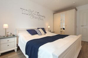 A neatly arranged bedroom with a bed, bedside tables, and a wardrobe. - Kurparkresidenz Apartment 14 - Kurparkresidenz (Scharbeutz)