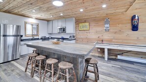 A modern kitchen with a wooden ceiling, stainless steel appliances, and a bar area with stools. - Camelback Cabin 8  Poconos (Tannersville)