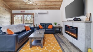 A cozy living room with a fireplace, leather sofas, and a flat-screen TV. - Camelback Cabin 8  Poconos (Tannersville)