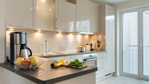 A modern kitchen with a central island, stainless steel appliances, and a view to the outside.