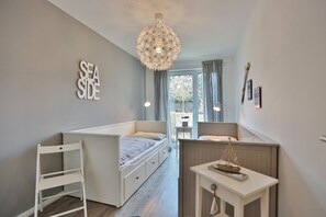 Un dormitorio compacto con una litera, un escritorio pequeño y una lámpara colgante.