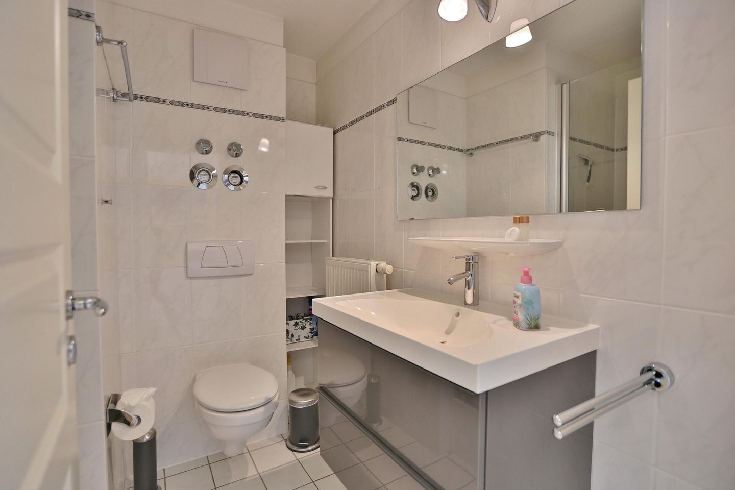 A modern bathroom with a toilet, bidet, and a sink with a mirror above it.