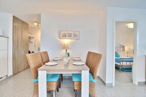 A dining area with a wooden table, four wicker chairs, and a framed picture on the wall.