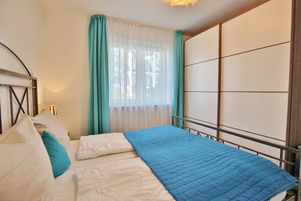 A bedroom with a bed, curtains, and a headboard.