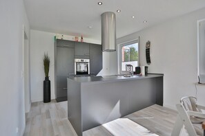 Eine moderne Küche mit Kochinsel, integriertem Backofen und einem großen Fenster für natürliches Licht.