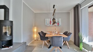 A modern dining area with a black wood-burning stove, a table set for four, and a painting above the table.