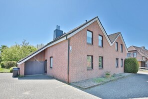 A two-story brick house with a sloped roof, a garage, and a small garden area. - Am Knurrhahn Apartment 2*** - Semi-detached house Am Knurrhahn (Scharbeutz)