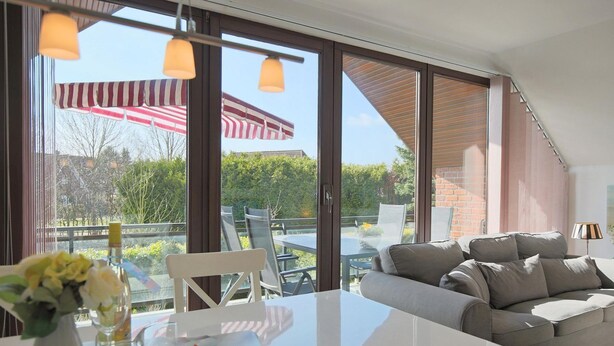 A modern living room with a large glass door leading to an outdoor patio.