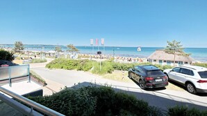 En kustvy med en strand, parkerade bilar och en byggnad med ett halmtak.