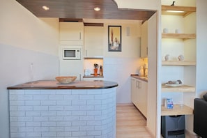 A compact kitchen with a white brick island, a microwave, and a small sink.