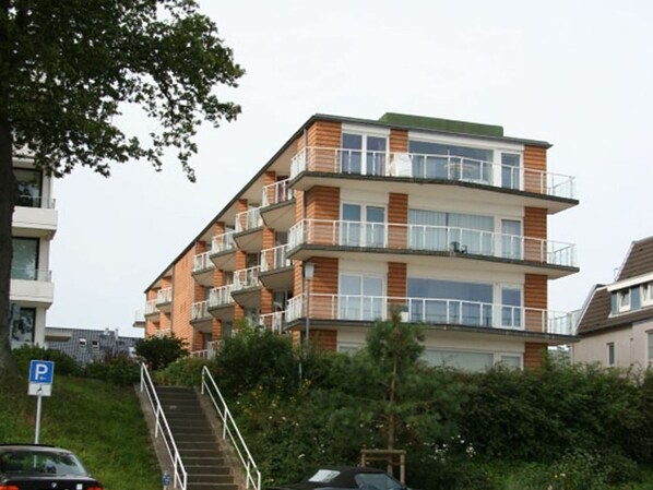 A multi-story residential building with balconies, a parking sign, and a staircase leading to the entrance. - Montemare House - Montemare House Apartment 1 (Scharbeutz)