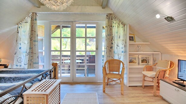 Une chambre confortable avec un lit, une chaise, un bureau et une grande fenêtre avec des rideaux.