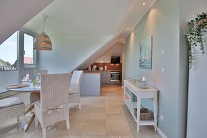 Un appartement moderne de style « loft », comprenant un coin repas, une cuisine et une grande fenêtre offrant une vue dégagée.