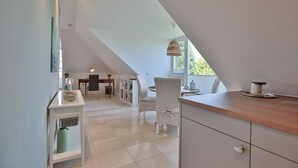 Una cocina moderna con techo alto y comedor con sillas de mimbre.