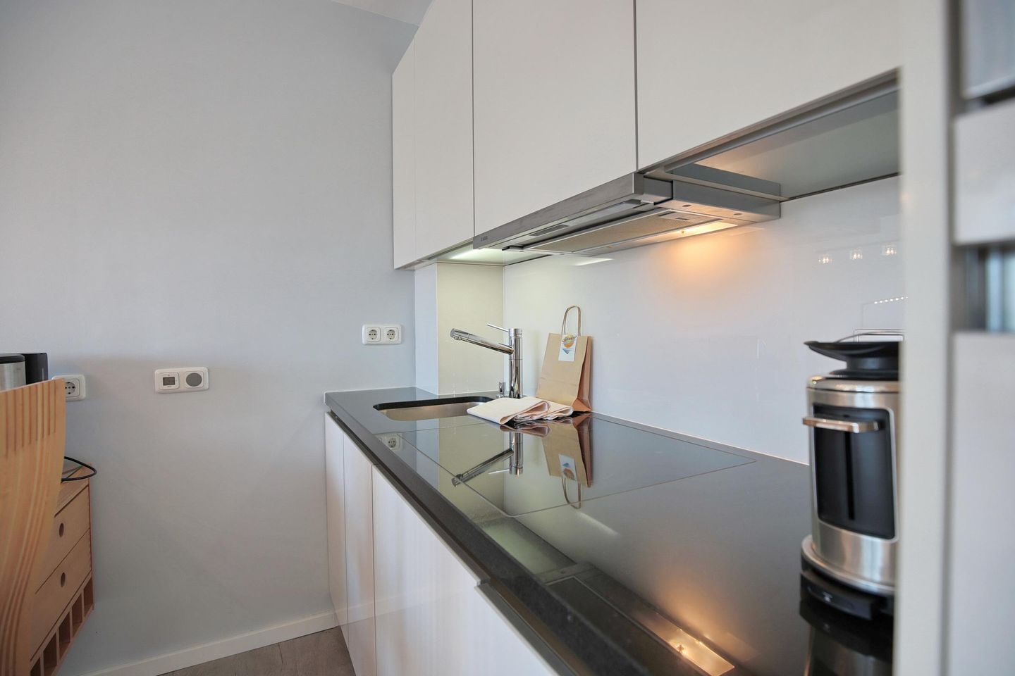 A modern kitchen with white cabinets, a black countertop, and stainless steel appliances.
