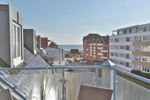 Een balkon met uitzicht op een complex aan de kust, met meerdere balkons en een helder zicht op zee.