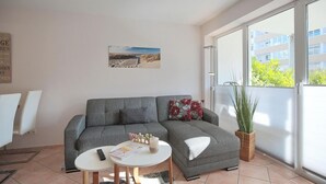 A living room with a grey sofa, a small round table, and a potted plant.