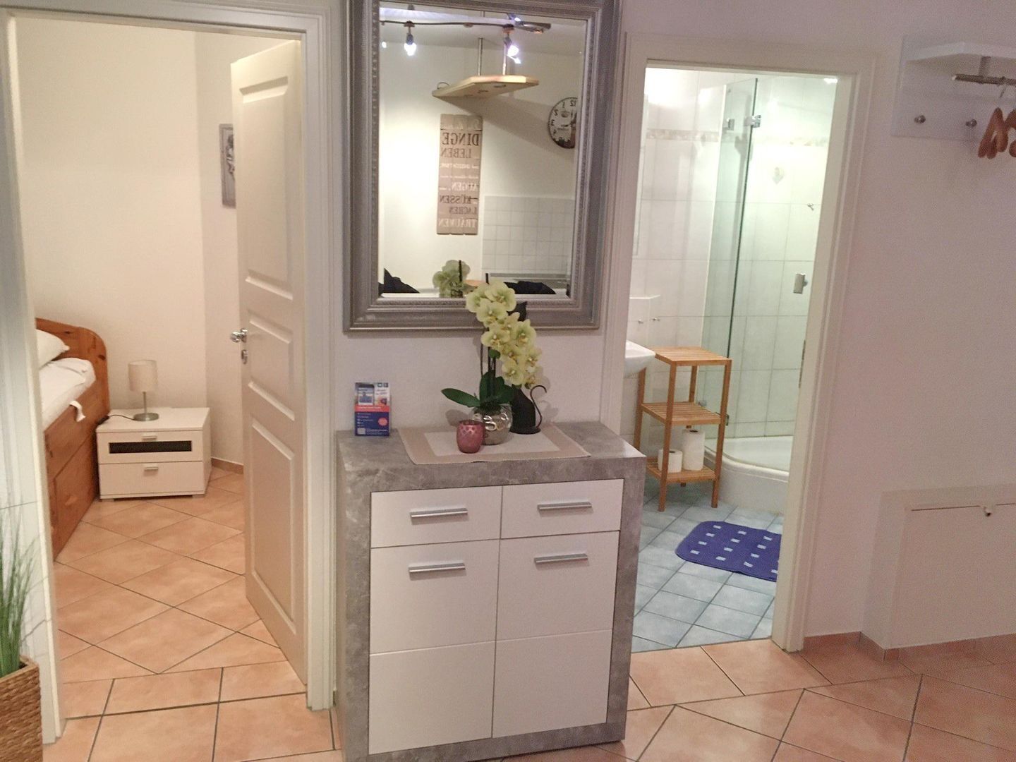 A bathroom with a shower, a sink with a mirror, and a toilet.