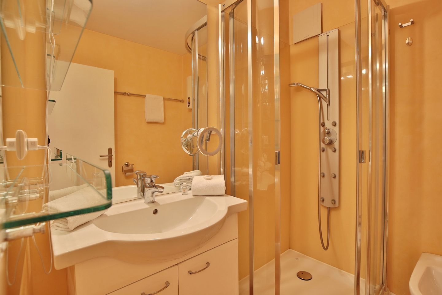 Une salle de bain moderne avec une douche à parois de verre, un lavabo avec un miroir et des toilettes.