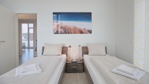 A hotel room with two beds, a large window, and a painting of a landscape.