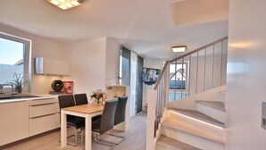 Eine moderne Küche mit Essbereich, einer Treppe und einem Fernseher im Hintergrund.