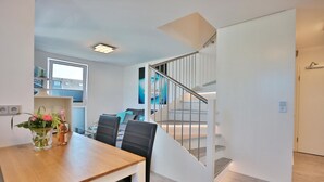 Eine moderne Küche mit weißen Schränken, einer Holztischplatte und einem Essbereich mit Tisch und Stühlen.