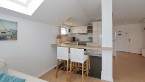 A modern kitchen with a skylight, white cabinets, and a dining area with bar stools.