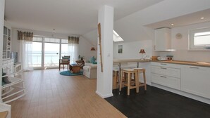 A modern apartment with a living room, dining area, kitchen, and balcony with a view.