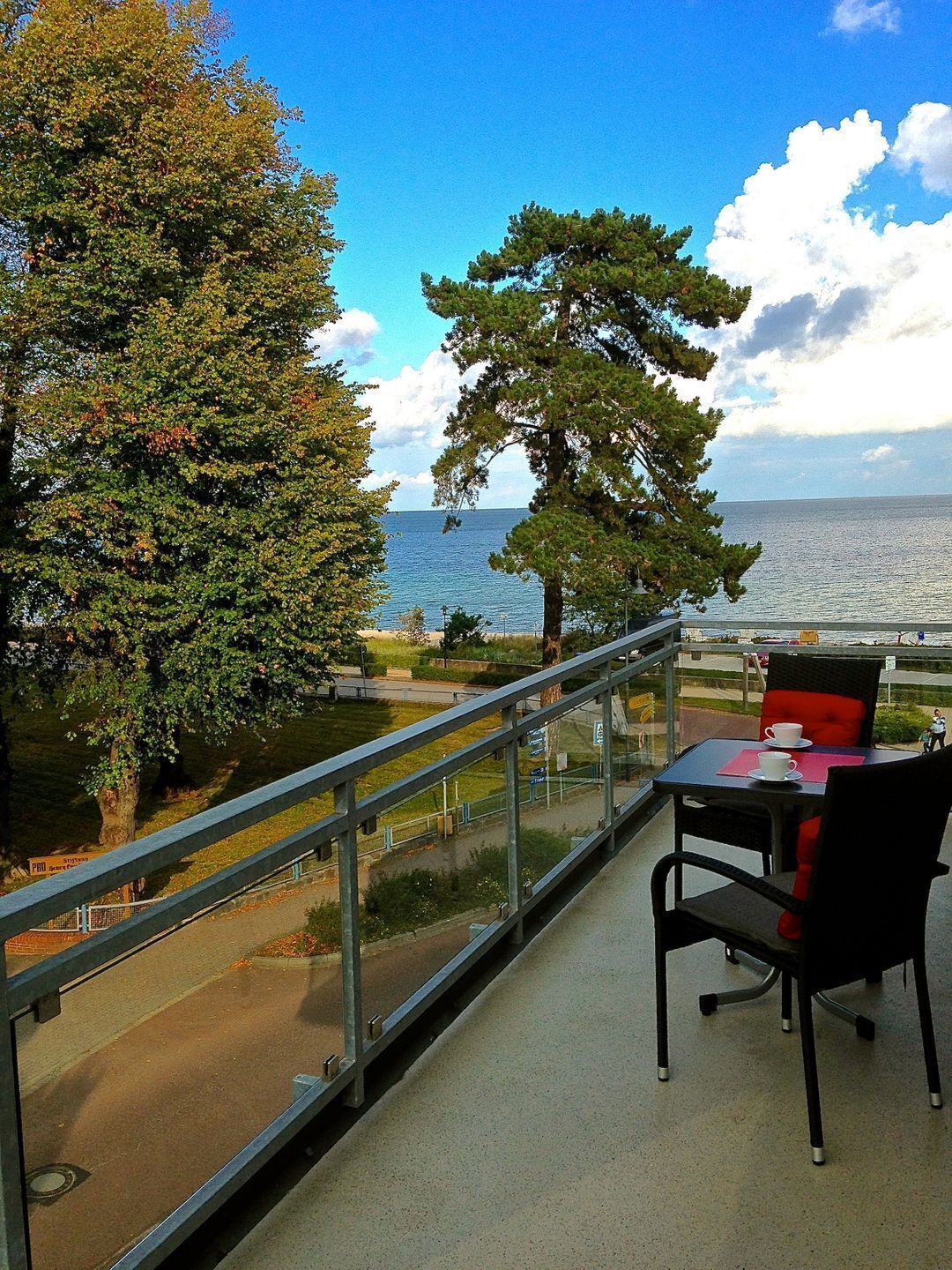 A balcony with a table and chairs, overlooking a body of water and trees.