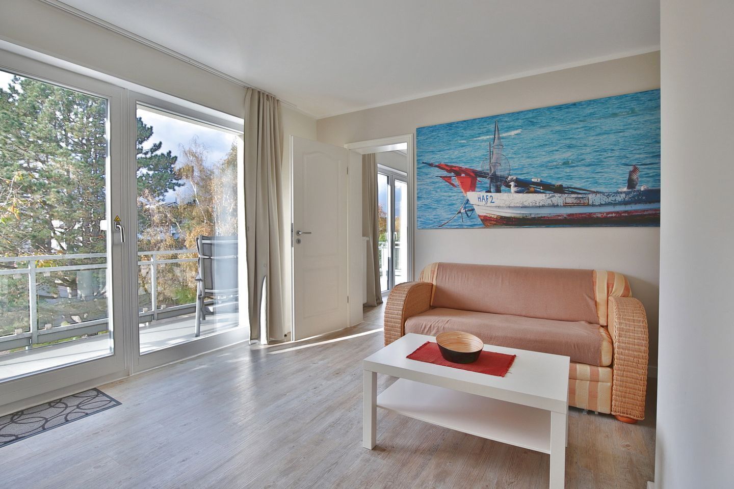 Ein modernes Wohnzimmer mit einer Couch, einem Couchtisch und einem Gemälde eines Segelbootes.