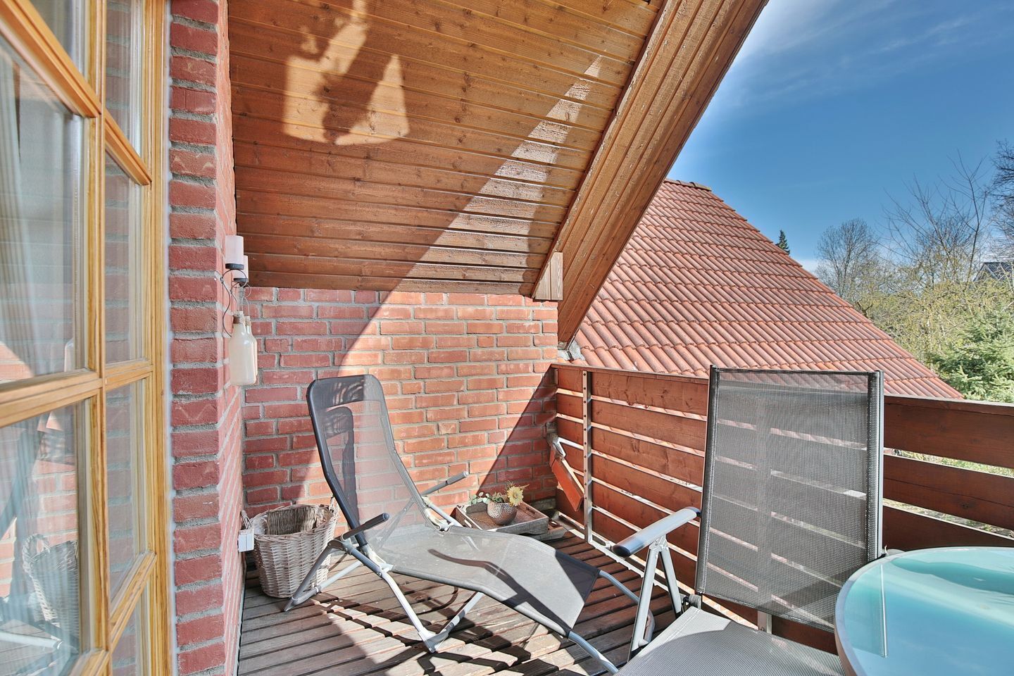Un espacio al aire libre cubierto con techo de madera, pared de ladrillo y tejado de tejas rojas.