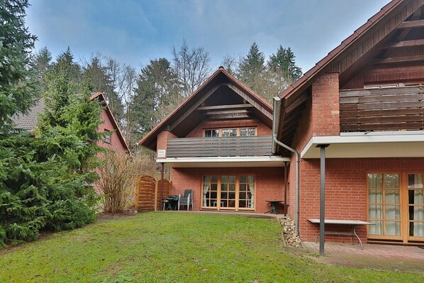 A two-story house with a brick exterior, a covered patio, and a small garden area.