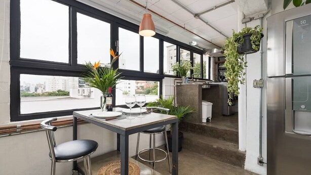 Una cocina moderna con comedor, ventanas amplias y plantas colgantes.