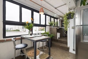 Een moderne keuken met een eethoek, grote ramen en hangende planten.