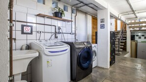 Un área de lavandería con lavadora, secadora y un cartel de no fumar.
