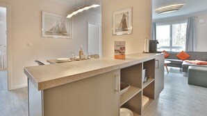 A modern kitchen with a central island, a dining area with a sofa, and a view of the outdoors.