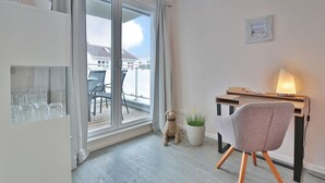 A modern apartment with a balcony, a desk with a lamp, and a chair.