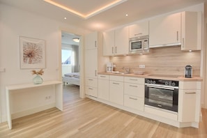 Een moderne keuken met witte kasten, een ingebouwde magnetron en een oven.